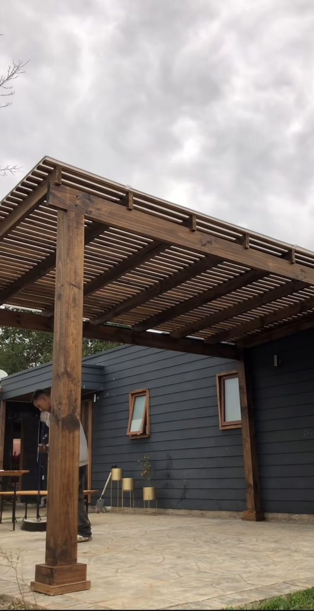 Pérgola de madera con empalillado y techo de policarbonato adosada a una casa