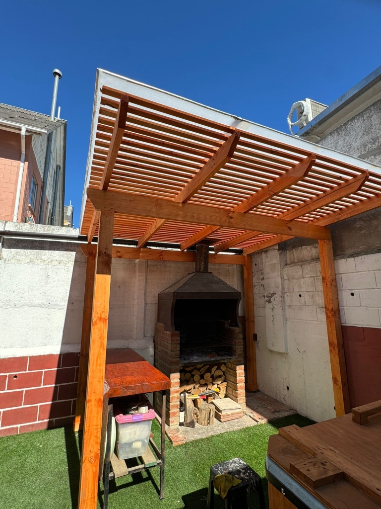 Pérgola de madera techada sobre quincho y parrilla