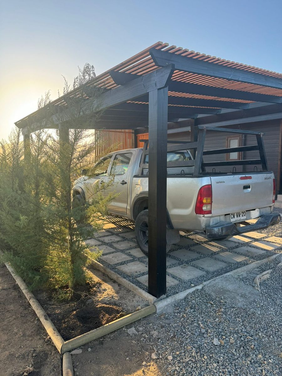 Cobertizo de madera y estructura negra sobre una camioneta, al atardecer