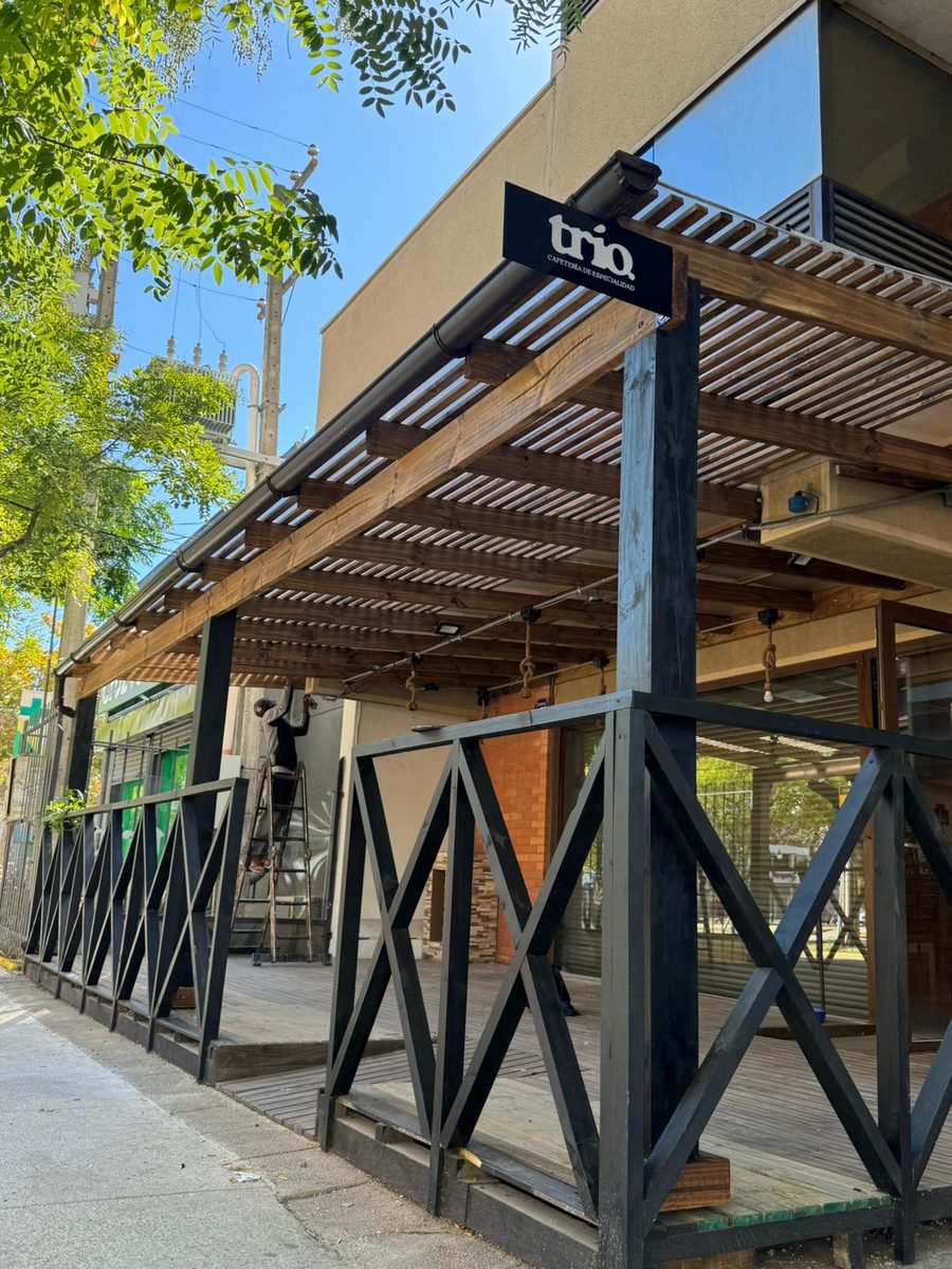 Pérgola metálica negra sobre la fachada y la vereda de un local comercial