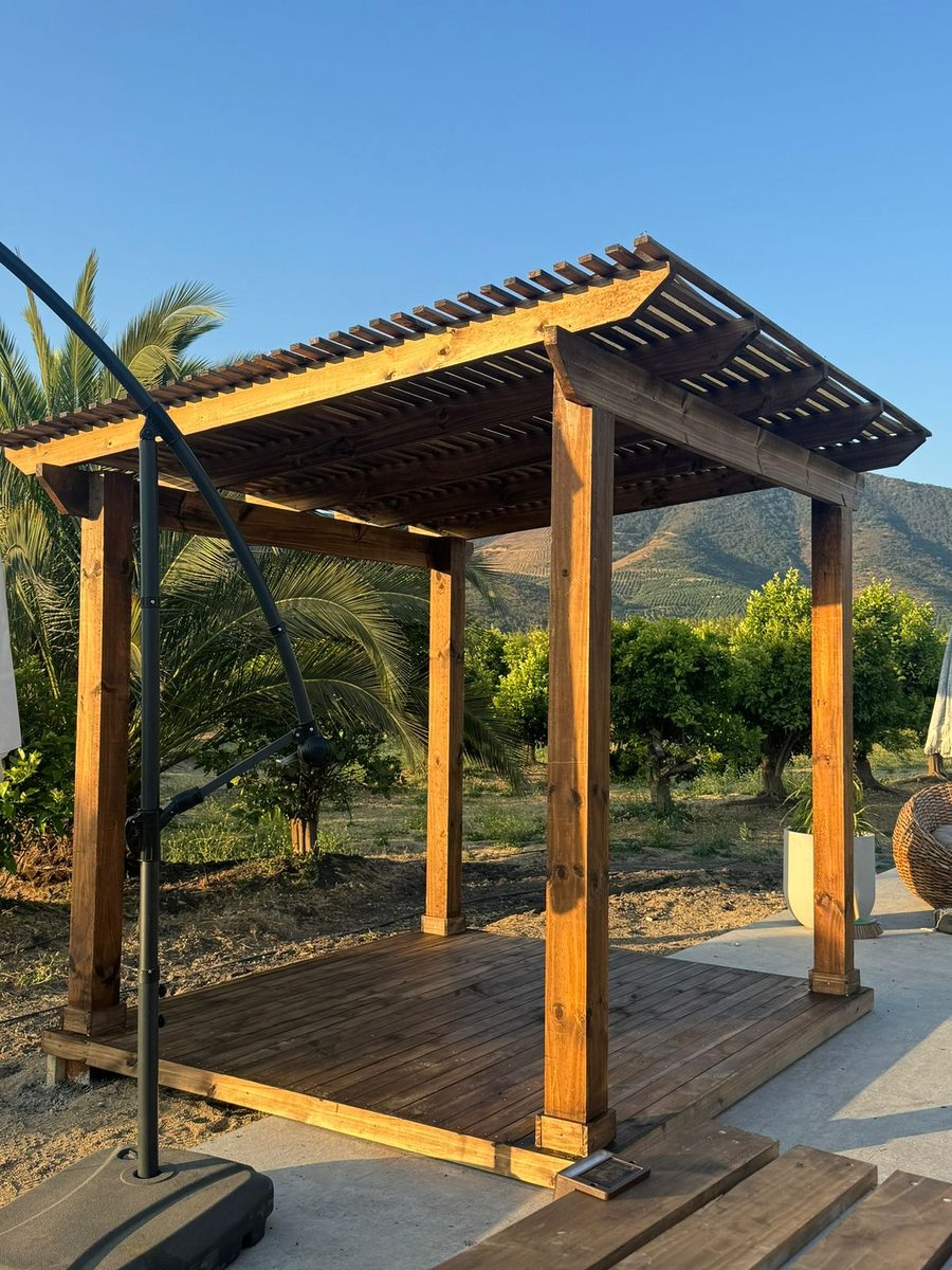 Pérgola de madera con piso de terraza en un patio de campo